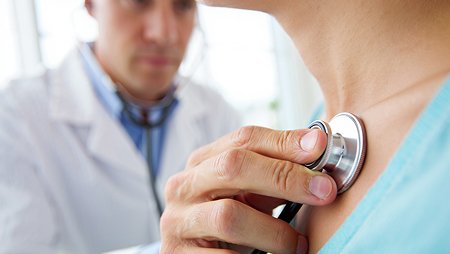Врач слушает стетоскопом пациента